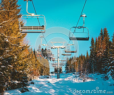 Cable chair lifts at a ski resort with skiers riding to the top of the slopes Editorial Stock Photo