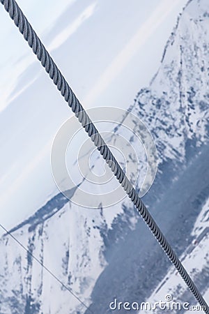 A cable from a ski lift at a height with a background of snowy Altai mountains. Rock climbing and construction Stock Photo