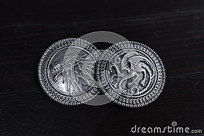 Metal medals inspired by the Stark house shields and Targaryen from the TV series Game of Thrones for sale as amulets. Editorial Stock Photo