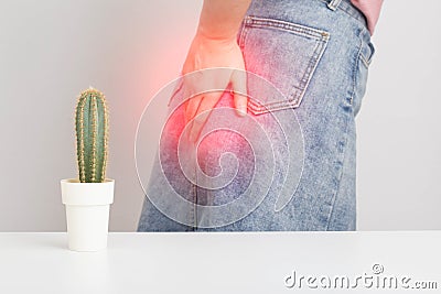 A cactus in the foreground, in the background a girl in a skirt is holding her anus with her hand. Hemora and proctitis Stock Photo