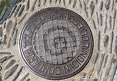 Cast iron manhole cover or gully cover on a street. Close up a manhole cover on road of Cadaques, Spain. Editorial Stock Photo