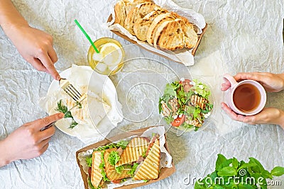 Caesar salad, bruschetta, ham and tomato sandwiches table with hands, top view from above Stock Photo