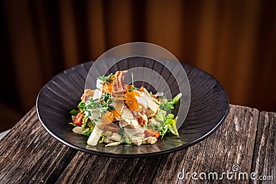 Caesar salad with fresh vegetables and crispy chicken on wooden background Stock Photo