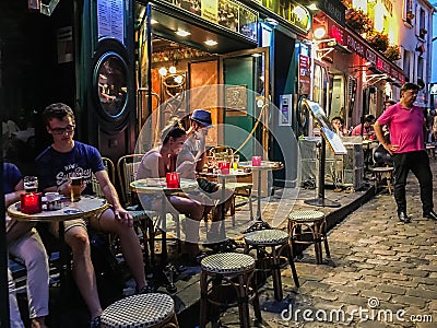 Cafe diners read and chat at Montmartre cafe on a summer evening Editorial Stock Photo