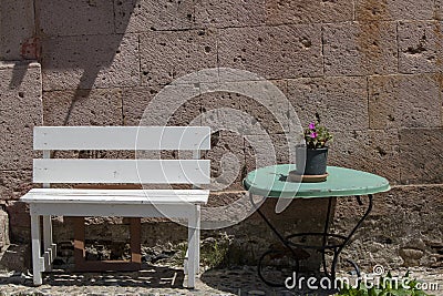 Cafe tables and chairs and pink flowers in the street. People walking on the street Stock Photo