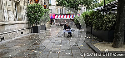 Cafe waiter takes a break on Paris plaza, checks cell phone Editorial Stock Photo