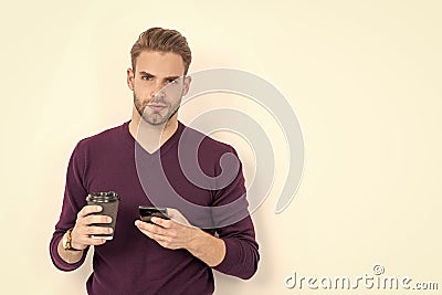 Caffeine and smartphone addiction. Handsome man use phone drinking coffee. Addiction to technology Stock Photo