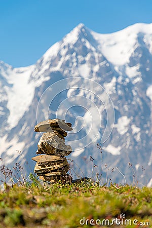Cairn at mountains summit - stacked rocks ahead of snow mountain peaks Stock Photo