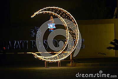 Cairo, Egypt, April 17 2023: A crescent made with led lights with Ramadan Fanous lamp lantern in the street as a festive sign Editorial Stock Photo