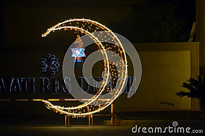 Cairo, Egypt, April 17 2023: A crescent made with led lights with Ramadan Fanous lamp lantern in the street as a festive sign Editorial Stock Photo
