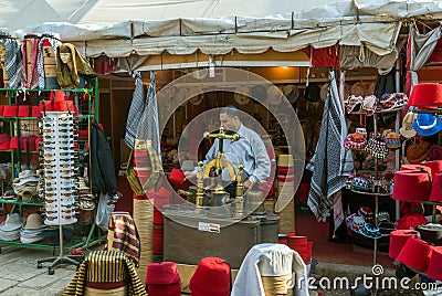 Shop selling hats called fez or tarbush and Egyptian headdresses with the seller making hats and the machine to make Editorial Stock Photo
