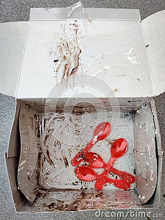 Cake box and spoons with cream strains after Stock Photo