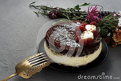 Cake covered with chocolate decorated raspberries, with a bouquet of flowers on a gray background. Stock Photo