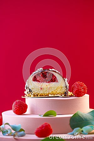 cake with raspberry filling cut and raspberries on a pink podium on a red background.Delicate airy cake souffle.Choux Stock Photo