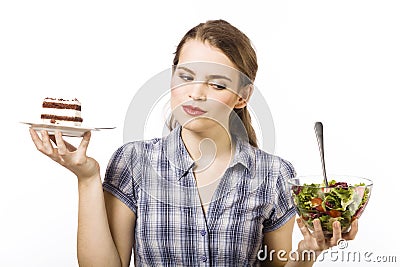 Cake or salad - that is the question. Beautiful young girl with a difficult choice Stock Photo