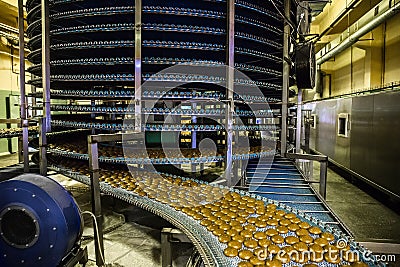 Cakes on automatic conveyor belt or line, process of baking in confectionery factory. Food industry, cookie production Stock Photo