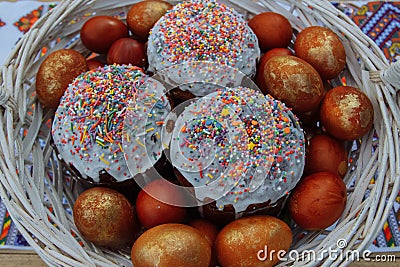 Cakes and painted eggs in a white basket Stock Photo