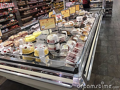 Cakes in refrigerated display in suburban supermarket bakery section. Wide selection of various cakes to entice customer Editorial Stock Photo