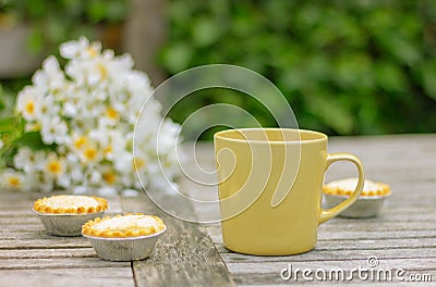 cakes and yellow cup on the table with white flowers in garden Stock Photo