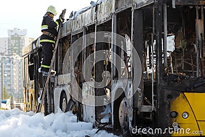 Cal Fire firefighter climbs a ladder by burnt traffic bus Stock Photo