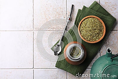 Calabash, bombilla, bowl of mate tea leaves and teapot on tiled table, flat lay. Space for text Stock Photo