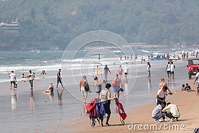 A lifeguard carrying lifejackets at the crowded tourist beach in Calangute in North Goa Editorial Stock Photo