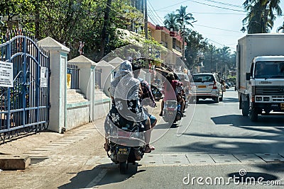 CALANGUTE, GOA, INDIA JANUARY 2, 2019: Motorcyclists and cars with passengers on street in India. Sunny day, moderate traffic Editorial Stock Photo