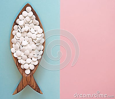 Calcium pills in a wooden dish in the form of a fish Stock Photo