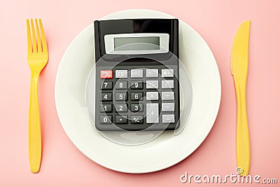 Calculate expensive food spending costs, counting calories and weight loss program concept with calculator onn empty plate, yellow Stock Photo