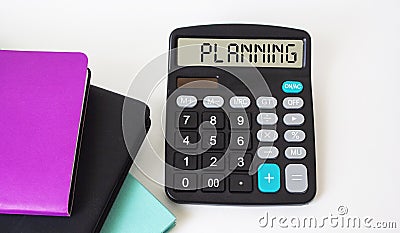 The calculator displays the text Planning, next to colored notebooks Stock Photo