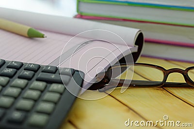 Calculator,eye glasses,pen,receipt and invoice book and stacked of books in the background. Stock Photo