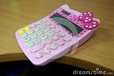 A cute pink calculator for calculating tools for children and adults is on the table Stock Photo