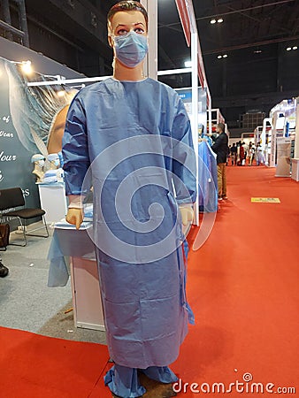 A model wearing mask, surgical apron, gloves , surgical shoe cover with a background of red carpet Editorial Stock Photo