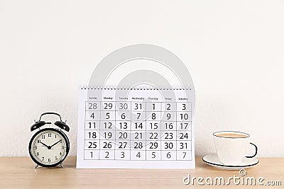 Calendar, alarm clock and cup of coffee on table Stock Photo