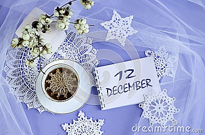 Calendar for December 12: a cup of tea with a decorative snowflake on a lace napkin, the name of the month December in English, Stock Photo