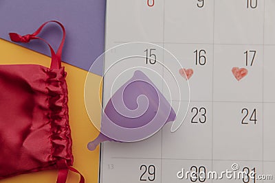 Calendar and menstrual cup with bag close-up. Woman critical days and hygiene protection Stock Photo