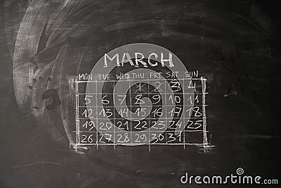 calendar month March is painted on a chalkboard. Stock Photo