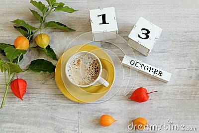 Calendar for October 13 : the name of the month in English, cubes with the number 13, a yellow cup with hot coffee, branches of Stock Photo