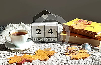 Calendar for September 24 : the name of the month in English, cubes with the number 24, a cup of tea, books, maple leaves on a Stock Photo