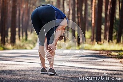 Calf muscle cramp. Woman feeling pain of her legs during running outdoors Stock Photo