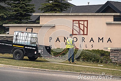 A landscaping worker applying some fertilizer or pesticide and weed control to a garden Editorial Stock Photo