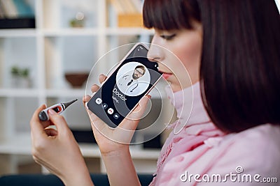 Call to a doctor. Close up of young ill woman with thermometer calling to male doctor for online consultation on Stock Photo