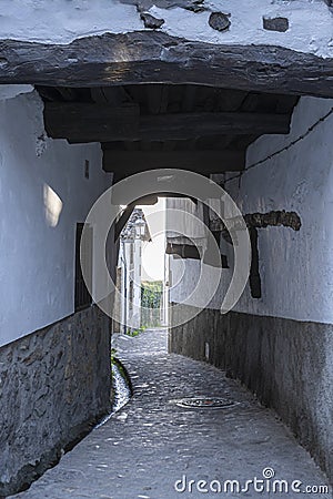 Callejuela estrecha y peatonal con soportal tradicional bajo las casas en la hermosa villa de Candelario, EspaÃ±a Editorial Stock Photo