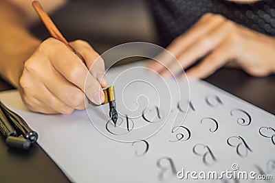 Calligrapher Young Woman writes phrase on white paper. Inscribing ornamental decorated letters. Calligraphy, graphic Stock Photo