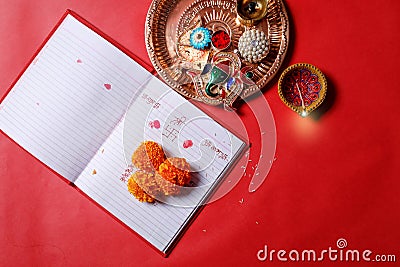 Calligraphy writing in hindi Shubha Labh means Goodness & Wealth, over Red accounting note book , diya, Stock Photo