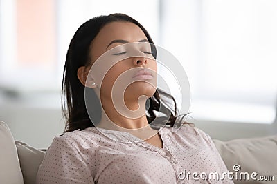 Calm African woman resting closed eyes breathing fresh humidified air Stock Photo