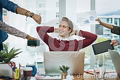 Calm amongst the chaos. a young businessman looking calm in a demanding office environment. Stock Photo