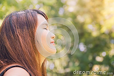 Calm beautiful smiling young woman with ponytail enjoying fresh air outdoor, relaxing with eyes closed Stock Photo