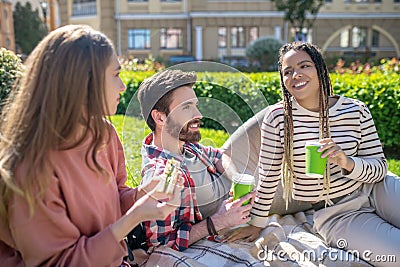 Calm guy and two happy girls with a sandwich and coffee. Stock Photo
