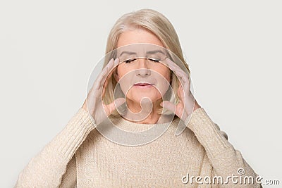 Calm healthy old woman massaging temples feeling stress relief Stock Photo